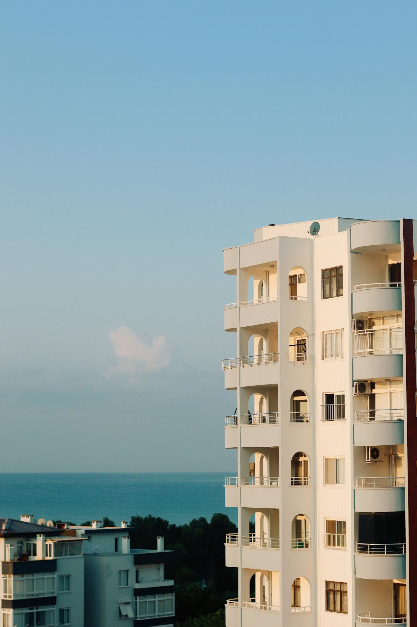 A modern apartment building near the sea with clear skies, perfect for urban living.
