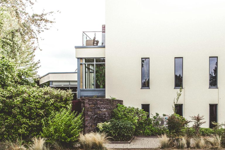 Elegant modern home exterior surrounded by lush greenery in Cork, Ireland.