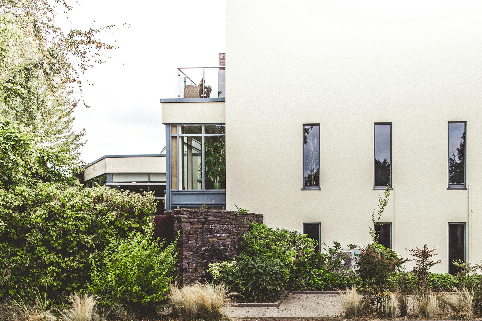 Elegant modern home exterior surrounded by lush greenery in Cork, Ireland.